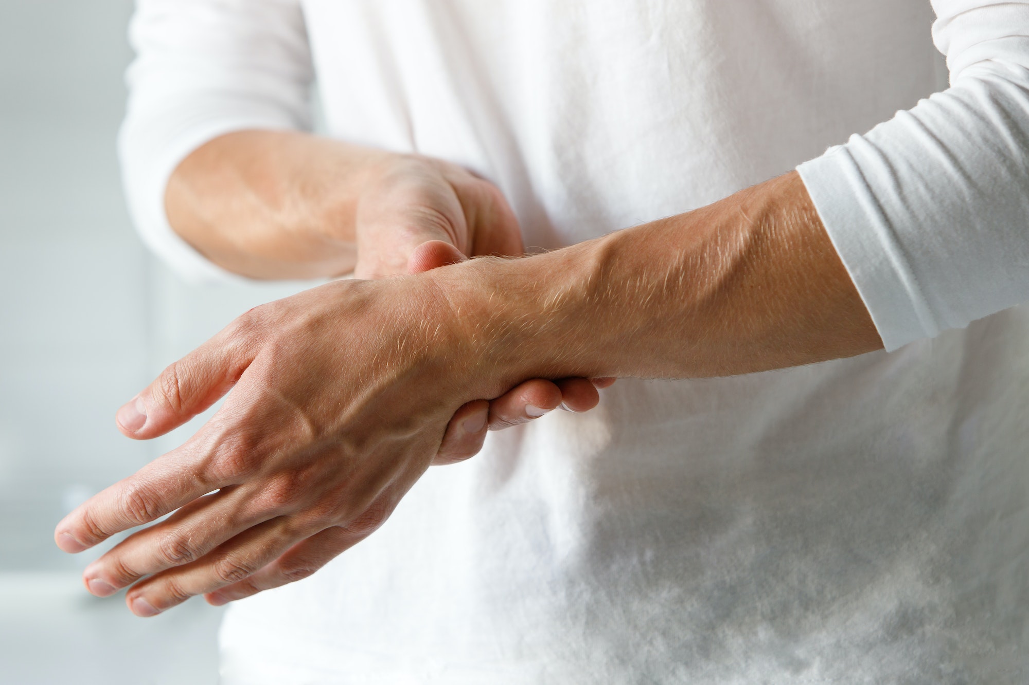 Closeup of man arms holding painful wrist caused by prolonged work on computer laptop. arthritis